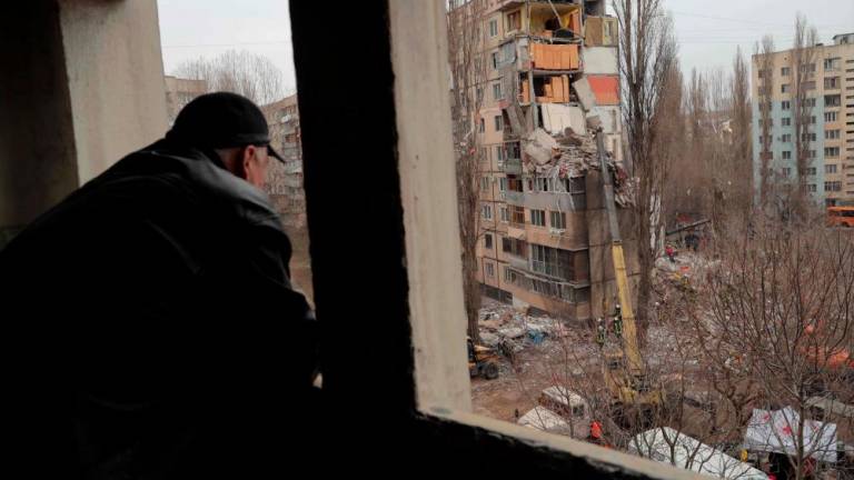 A local resident watches rescue works at the site of a heavily damaged multi-story apartment building, following a Russian drone attack, in Odesa, on March 2, 2024. - AFPPIX