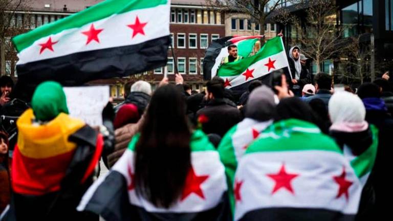 People wrapping themselves in Syrian flags gather in front of Duisburg Central Station. Christoph Reichwein/dpa
