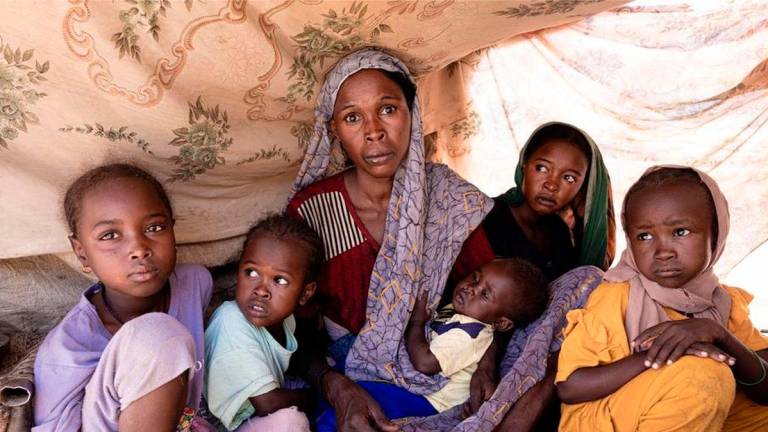 A displaced woman and some children sit under a tent built from logs and cloth in Tawila, North Darfur, Sudan, Aug. 8, 2025. (The UN World Food Programme/Handout via Xinhua)