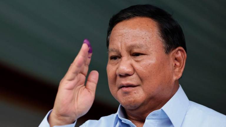 This photo taken on on February 14, 2024 shows Indonesia’s presidential candidate Prabowo Subianto gesturing after staining his fingers with ink at a polling station after he voted in Indonesia’s presidential and legislative elections in Bogor, West Java/AFPPix