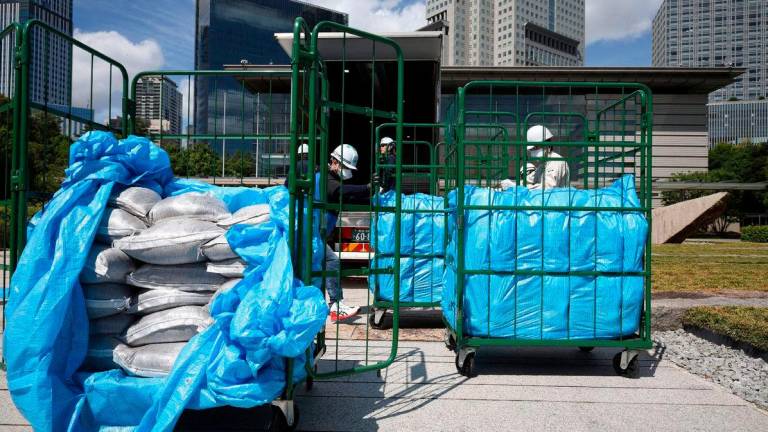 Workers unload bags of soil removed during decontamination following the Fukushima Daiichi nuclear power plant accident, at the Prime Minister’s office in Tokyo - AFPPix