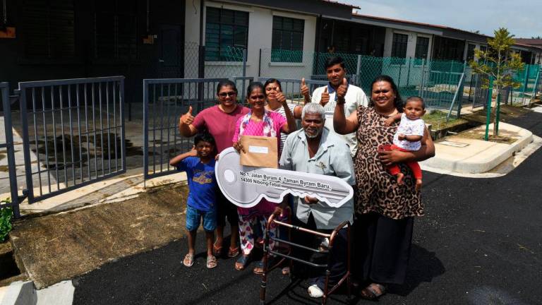 T. Kuppusamy, 73, (dua dari kanan) bersama isterinya, S. Malliga, 61, (dua dari kiri) serta ahli keluarga bergambar di hadapan rumah baharu mereka pada Majlis Perasmian Projek Penempatan Semula Penduduk Ladang Byram ke tapak baharu di Jalan Sungai Daun, Mukim II, Nibong Tebal, hari ini. - BERNAMA