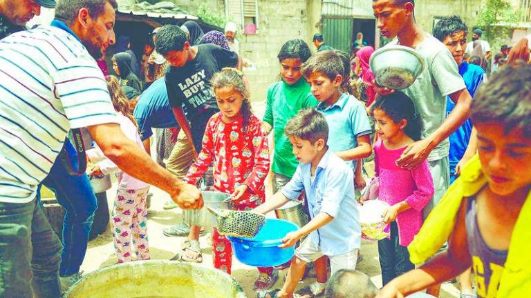 Displaced Palestinian children line up to receive food in Rafah, on the southern Gaza strip, on May 19 - AFPPIC