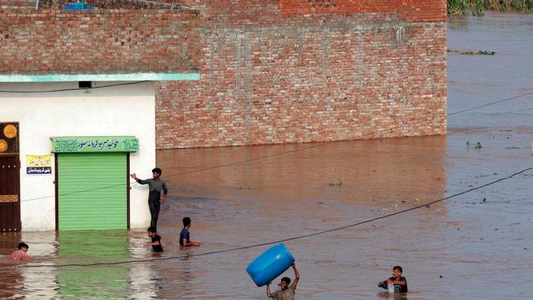 A man carries a plastic container as he moves through a water-logged residential area located on the banks of the flooded Ravi river, after India opened the gates of major dams on rivers in its part of Kashmir after the heavy rains, in Lahore, Pakistan, August 28, 2025. REUTERS/Mohsin Raza