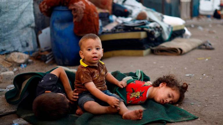 Children among displaced Palestinians fleeing northern Gaza due to an Israeli military operation rest on the way as they, along with others, move southward after Israeli forces ordered residents of Gaza City to evacuate to the south, in the central Gaza Strip, September 19, 2025. REUTERS/Mahmoud Issa