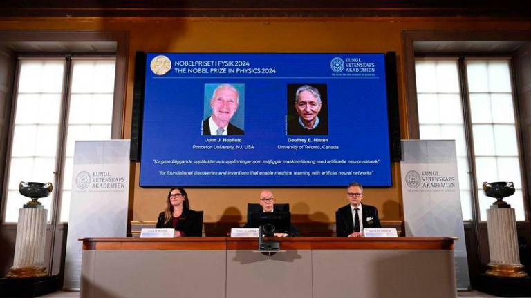 A screen shows the laureates of the 2024 Nobel Prize in Physics, US physicist John J Hopfield and Canadian-British computer scientist and cognitive psychologist Geoffrey E Hinton - REUTERSpix