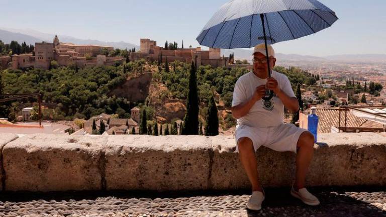 A tourist uses an umbrella at San Nicolas viewpoint in front of La Alhambra, during a hot summer day in Granada, Spain - REUTERSpix