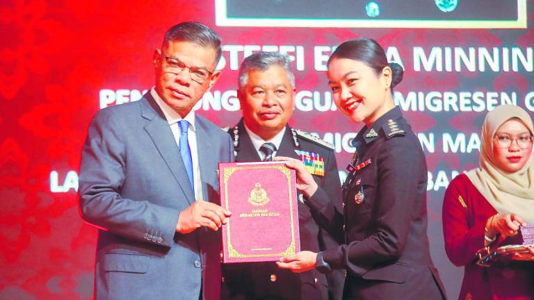Saifuddin Nasution, accompanied by Immigration Department Director-General Datuk Zakaria Shaaban, presenting an award at the department’s Excellent Service Awards ceremony in Putrajaya yesterday. – Amirul Syafiq/theSun