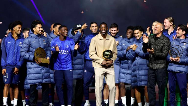 Paris Saint-Germain’s French forward #10 Ousmane Dembele (C) celebrates with the Ballon d’Or trophy and his teammates during a ceremony after the French L1 football match between Paris Saint-Germain (PSG) and Auxerre at the Parc des Princes stadium in Paris on September 27, 2025. (Photo by FRANCK FIFE / POOL / AFP)