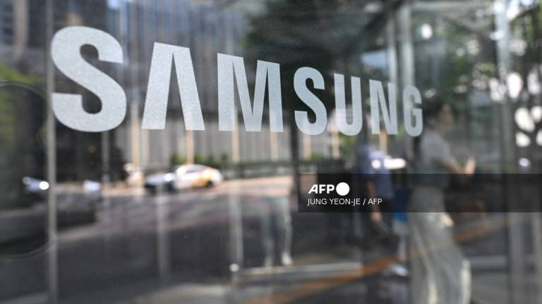 A woman walks past a logo of Samsung Electronics displayed on a glass door at the company's Seocho building in Seoul on July 8, 2025. - AFP
