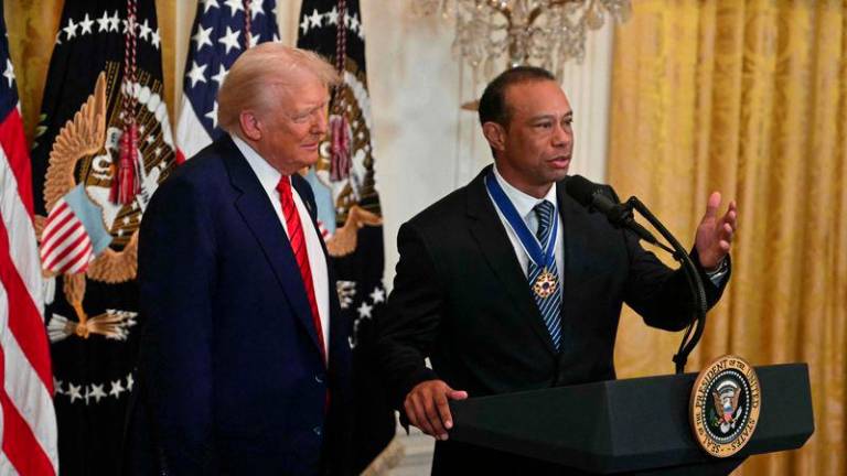 US golfing legend Tiger Woods speaks as President Donald Trump looks on during a reception for Black History Month in the East Room of the White House on February 20, 2025 in Washington, DC. - AFPPIX