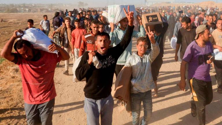 Palestinians carry aid supplies from the U.S.-backed Gaza Humanitarian Foundation, in Khan Younis, in the southern Gaza Strip - Reuterspix