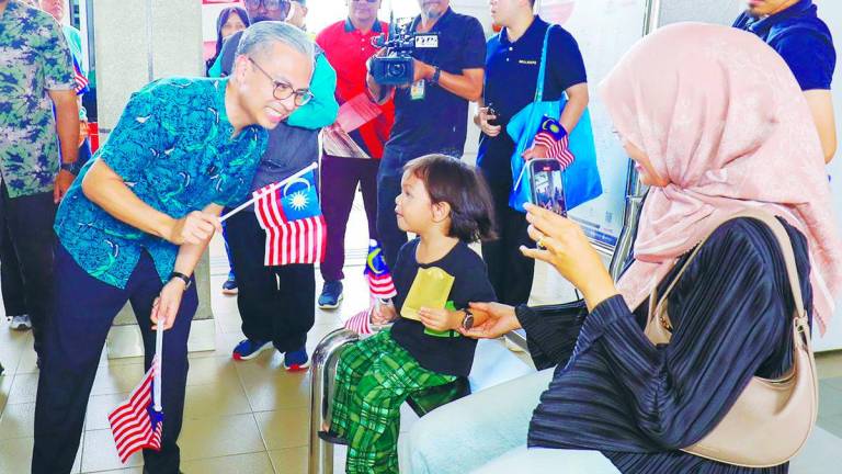 Fahmi waving the national flag with visitors at the launch event yesterday. – Adib Rawi Yahya/theSun