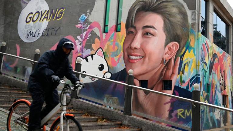 A man cycles past a mural depicting RM, a member of K-pop group BTS, in Goyang, northwest of Seoul, on December 11, 2023 - AFPPIX