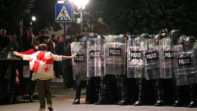 A protester wearing a Georgian flag walks towards police officers blocking the street during an opposition rally on the day of local elections in Tbilisi, Georgia October 4, 2025. REUTERS/Irakli Gedenidze
