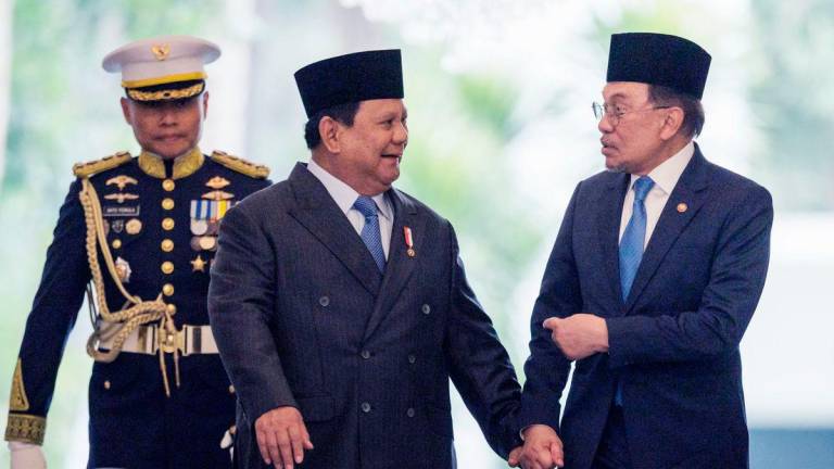 Malaysia’s Prime Minister Anwar Ibrahim (R) and Indonesia’s President Prabowo Subianto (C) walk together ahead of their bilateral meeting at the Presidential Palace in Jakarta on July 29, 2025. (Photo by Yasuyoshi CHIBA / AFP)