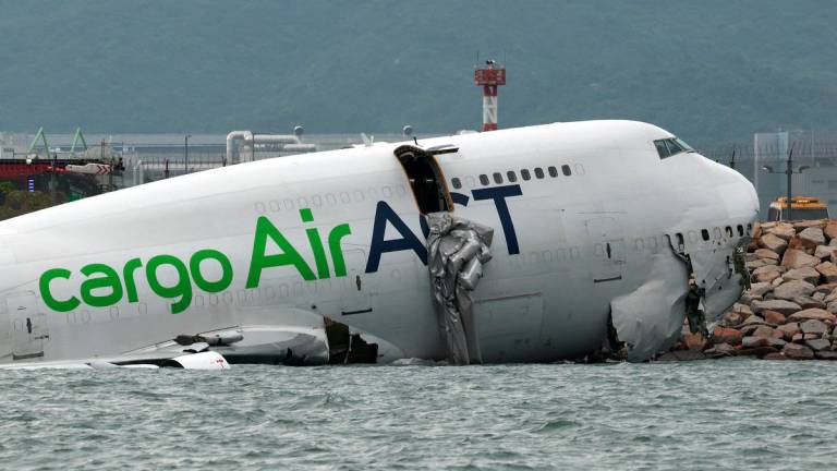 A cargo plane lies partially in the sea after veering off the runway during landing at Hong Kong International Airport in Hong Kong, China, October 20, 2025. - REUTERS/Tyrone Siu
