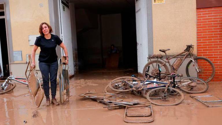 A woman carries out folding chairs caked in mud after torrential rains caused flooding in La Alcudia, Valencia region - REUTERSpix