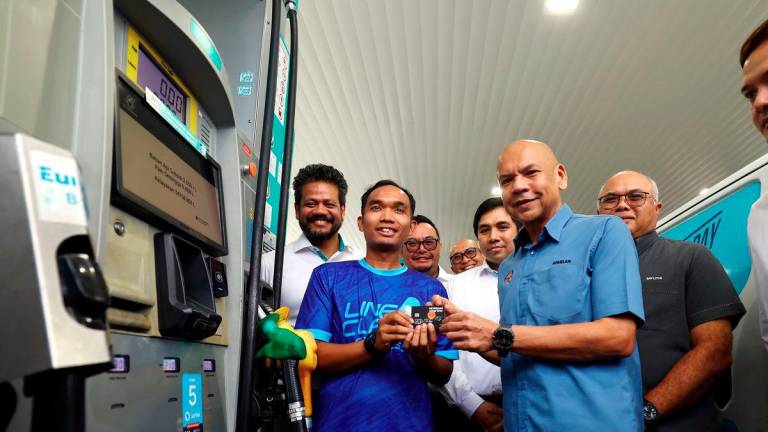 Menteri Perdagangan Dalam Negeri dan Kos Sara Hidup Datuk Armizan Mohd Ali bersama kakitangan Line Clear Express Sdn Bhd Muhammad Azim Asyraf Nasaruddin yang menerima kad fleet bagi kenderaan syarikat pada Majlis Penyerahan Kad Fleet di Stesen Minyak Petronas, Cyberjaya hari ini. - BERNAMA