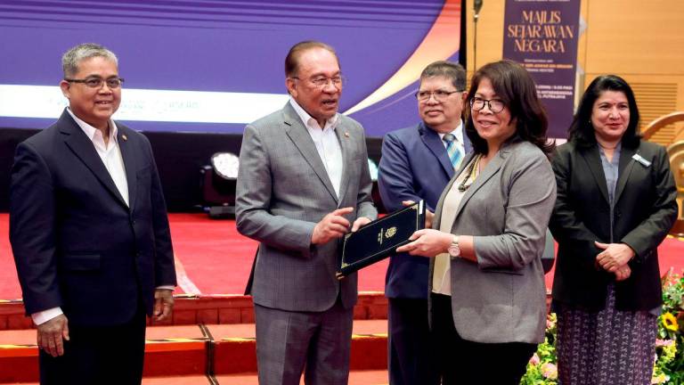 Anwar, accompanied by (from left) Johari and Saraswathy, presenting the National Historians Council membership certificate to Prof Dr Poline Bala at the event in Putrajaya yesterday. – BERNAMAPIC