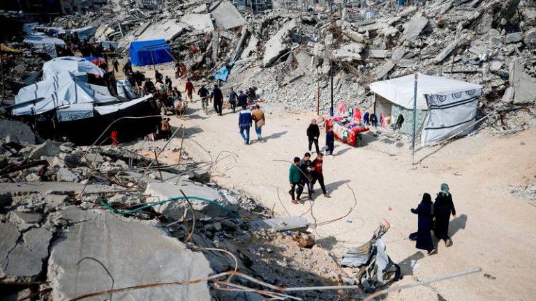 Palestinians walk on a street among the rubble of buildings destroyed during the Israeli offensive, amid a ceasefire between Israel and Hamas, at Jabalia refugee camp - REUTERSpix