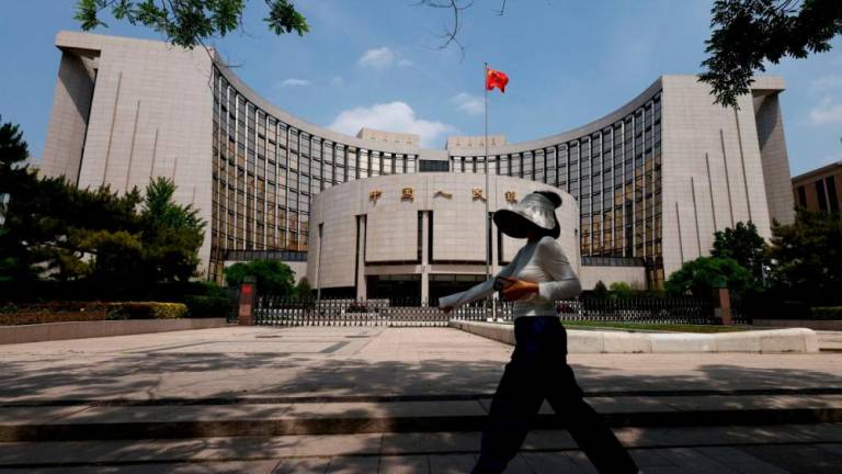 A person walks past the headquarters of the People’s Bank of China, in Beijing, China May 7, 2025. REUTERSpix