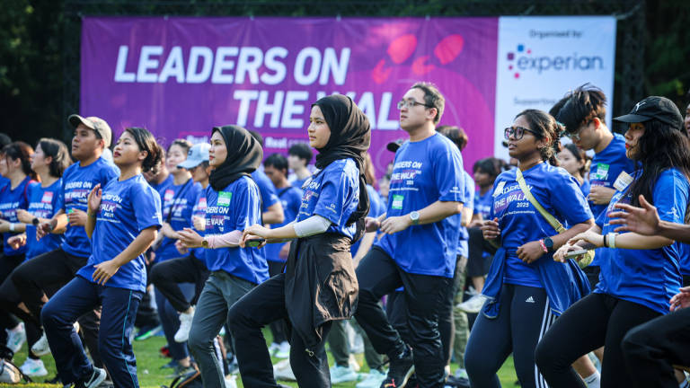 Participants do warm-up exercises during the Leaders On The Walks event at Perdana Botanical Garden today. - BERNAMA