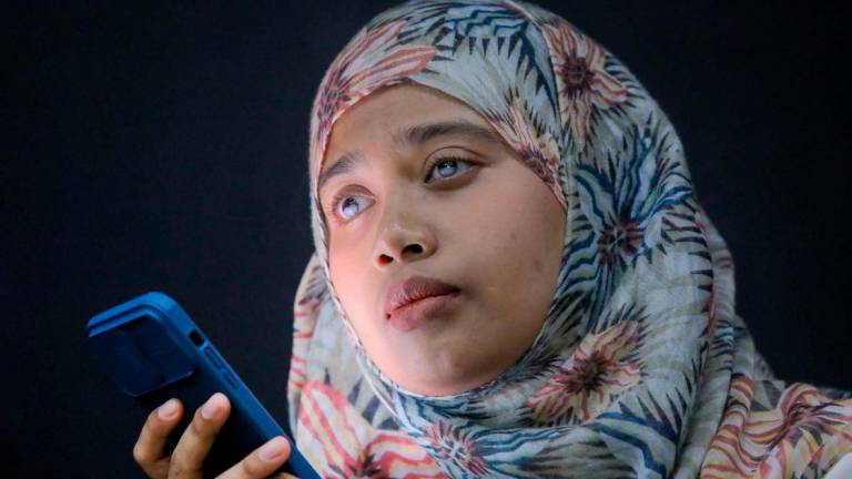 Sharifah Nur Jahan Syed Jakirul Alam, who is blind, using a voice-prompt feature on her smartphone during a separate interview with theSun. – ADIB RAWI YAHYA/THESUN