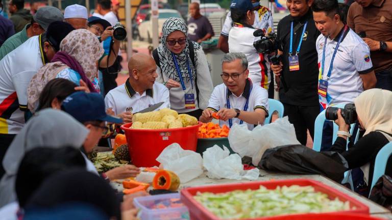 Menteri Komunikasi Datuk Fahmi Fadzil bersama Menteri Perdagangan Dalam Negeri Dan Kos Sara Hidup Datuk Armizan Mohd Ali meluangkan masa bergotong royong, rewang bersama pendududuk Kampung Pachitan, Port Dickson, Negeri Sembilan untuk menyediakan juadah bagi program Kenduri Rakyat - BERNAMA