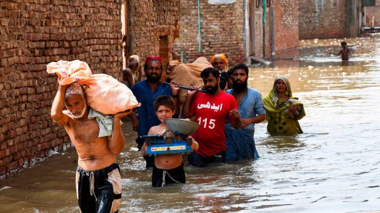 People wade through a flooded street as they carry a woman towards the hospital at Latifabad, Hyderabad, Pakistan, August 22, 2025. REUTERS/Yasir Rajput TPX IMAGES OF THE DAY