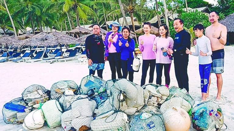 Tan (third right) beside Esther during the beach cleanup. – Pic courtesy of Berjaya Group