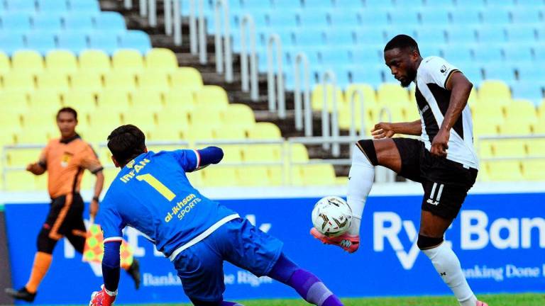Terengganu FC player Yann Kevin Mabella (right) controls the ball against Imigresen FC goalkeeper Muhammad Zarif Irfan Hashimuddin during the FA Cup match at the Penang State Stadium here today. - BERNAMA