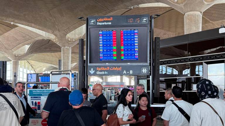 People stand in front of a flight information display screen showing information about delayed and cancelled flights, at Queen Alia International Airport in Amman, Jordan June 13, 2025. - REUTERSPIX