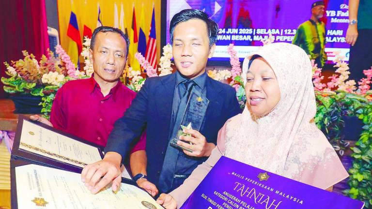 The best student in the blind category, Nik Muhammad Ahnaf Rujhiee Raja Anuar, shares joy with his parents during the award ceremony for the best students in STPM, MUET and SKBMW 2024 at the Malaysian Examinations Council complex in Kuala Lumpur yesterday. – Adib Rahwi Yahya/theSun