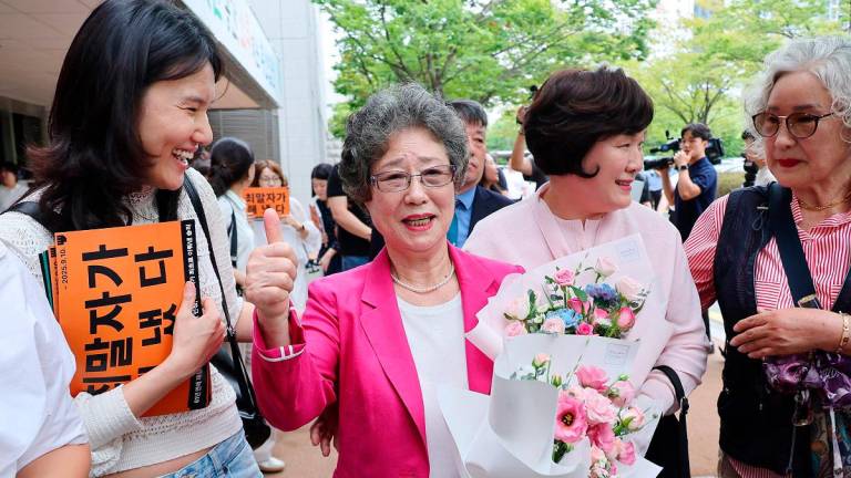 Choi Mal-ja (C), who was convicted 61 years ago for biting off the tongue of her attempted rapist, reacts after her retrial at the Busan District Court in Busan on September 10, 2025. - YONHAP / AFP