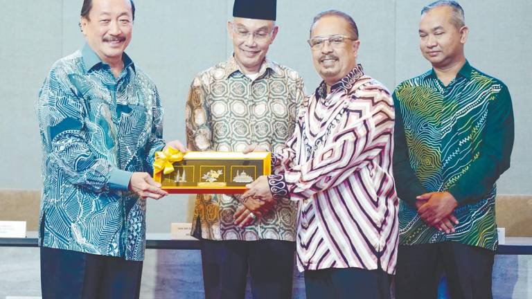 Tan (left) presenting a token of appreciation to Syed Tajul Arif after the MoU signing between Berjaya Land and Impianan Utara, witnessed by Mohd Shukri Ramli (second left) and MBI Perlis acting CEO Ahmad Hishamudin Johari. – AMIRUL SYAFIQ/THESUN
