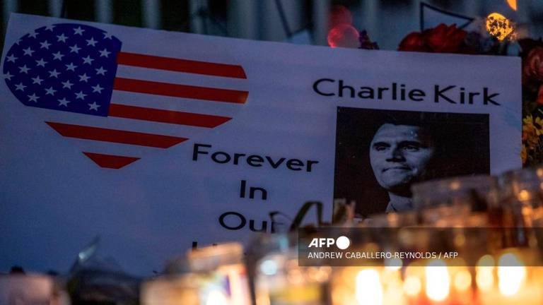 Candlelights illuminate a note left at a makeshift memorial for right-wing activist and Turning Point USA founder Charlie Kirk outside of their headquarters in Phoenix, Arizona, on September 20, 2025. - AFP