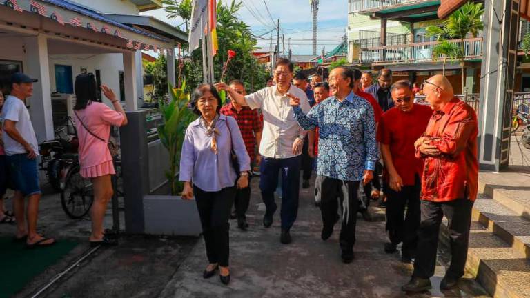 Tan, guided by Lim (white shirt), visits a village in Pulau Ketam during his first visit to the island. THESUN/AMIRUL SHAFIQ