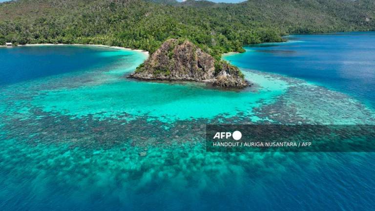 A handout aerial picture taken in December 2024 and released on September 24, 2025 by Indonesian NGO Auriga Nusantara shows coral reefs surrounding Batang Pele Island in Raja Ampat, Southwest Papua. AFP PHOTO / AURIGA NUSANTARA