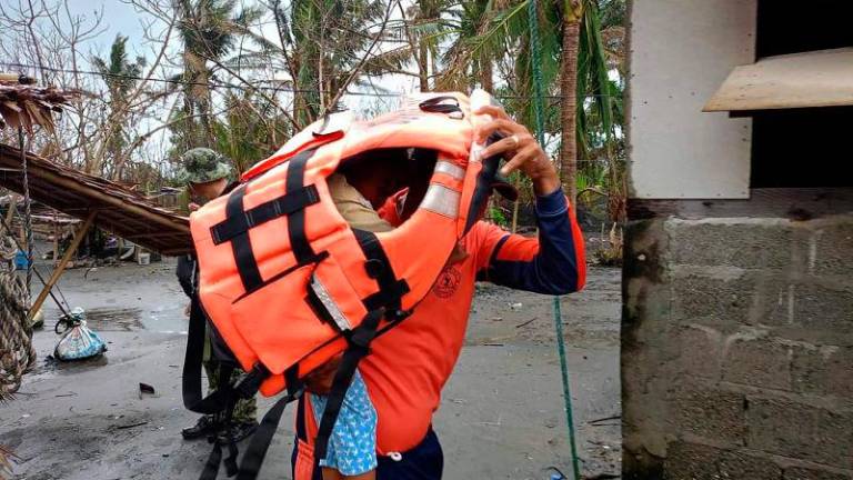 This handout photo taken on November 14, 2024 and released by Buguey Municipal Disaster Risk and Reduction Management Office via Cagayan Provincial Public Information office shows a rescuer carrying a young resident during a forced evacuation operation in Buguey town, Cagayan province, north of Manila, ahead of Super Typhoon Usagi’s landfall. - AFPPIX