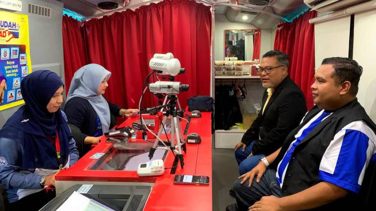 Seorang pengunjung, Mohd Shahir Khassin, 38 (kanan) mengambil peluang memperbaharui kad pengenalan di Bas Mekar Jabatan Pendaftaran Negara (JPN) pada Program MADANI Rakyat (PMR) 2025 Kelantan di perkarangan Stadium Sultan Muhammad IV , semalam - BERNAMA