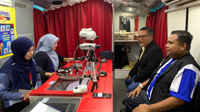 A visitor, Mohd Shahir Khassin, 38 (right), takes the opportunity to renew his identity card at the National Registration Department’s (JPN) Mekar Bus during the 2025 Kelantan MADANI Rakyat (PMR) Programme at the compound of Sultan Muhammad IV Stadium today. – BERNAMA