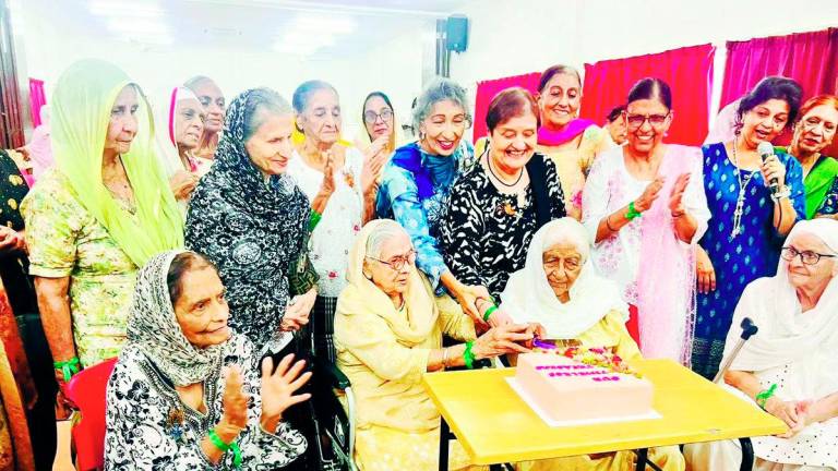 Some elderly members of the community celebrating together by cutting a cake.