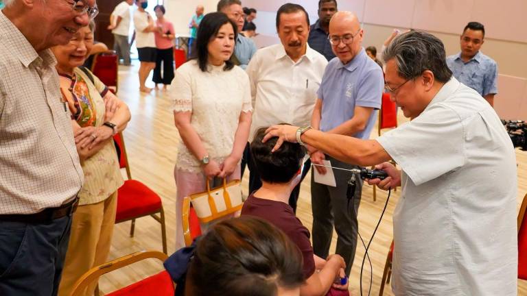 Tan (centre) and his wife Puan Sri Esther and Chin watching a volunteer doctor examine a participant during the event. – AMIRUL SYAFIQ/THESUN