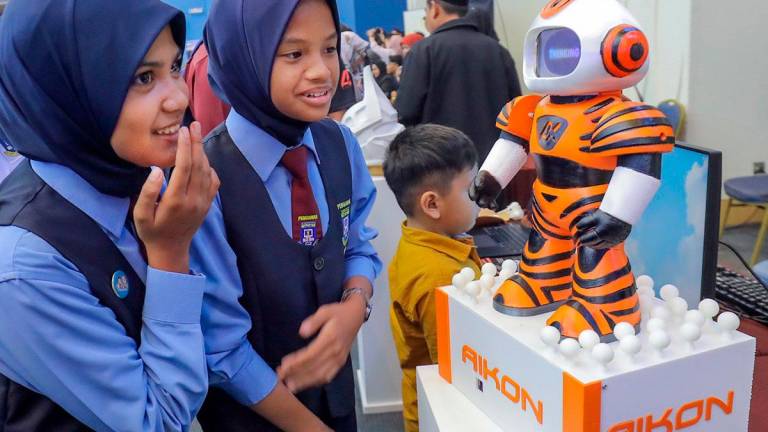 FUTURE IN FOCUS ... Students marvel at an AI robot showcased at the AI Grand Prix 2025 Conference yesterday. The event, launched by Fahmi, discussed AI’s impact on communication, media and the digital landscape. – ADIB RAWI YAHYA/THESUN