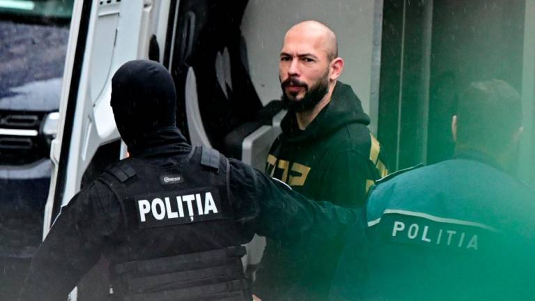 British-US former professional kickboxer and controversial influencer Andrew Tate (C) is led by police officers to the Court of Appeal in Bucharest, Romania on March 12, 2024, following his and his brother's arrest over UK sex offence charges. - AFPPIX