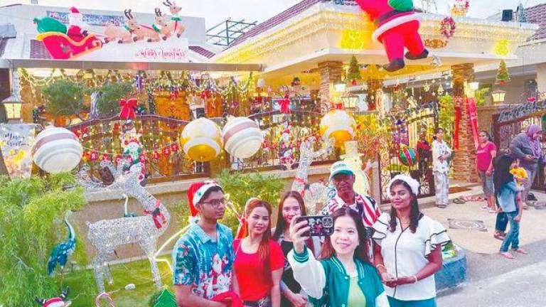 Visitors pose with house owner Charles Dorney (wearing cap), his wife Christe Samasundram (right) and son Dohnaven. – MASRY CHE ANI/THESUN