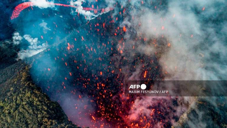 A picture taken with a drone on March 16, 2021 shows members of a local search and rescue squad taking pictures of Klyuchevskoy volcano eruption on Russia's far eastern Kamchatka peninsula. - Maxim FESYUNOV / AFP