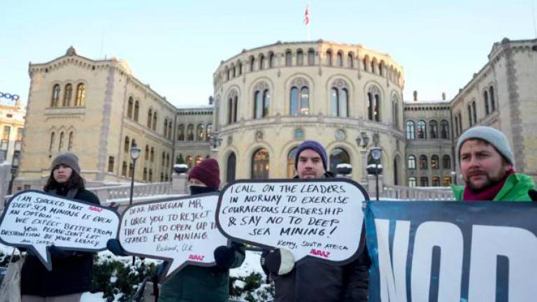 Protesters hold placards during a demonstration against seabed mining outside the Norwegian Parliament building in Oslo - AFPPIX