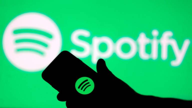 A smartphone is seen in front of a screen projection of Spotify logo, in this picture illustration taken April 1, 2018. - REUTERS